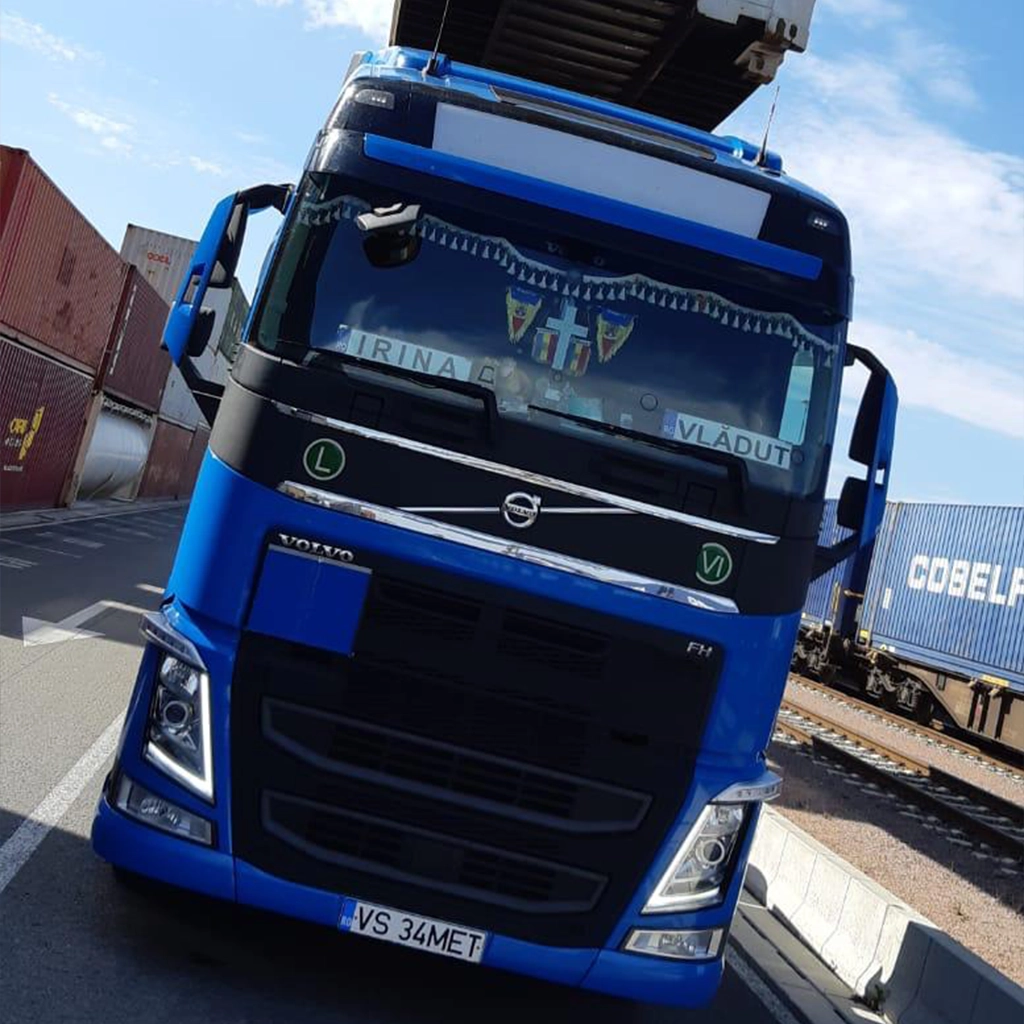 Camion Volvo fotografiat intr-un port european in timp ce semiremorca e incarcat cu un container