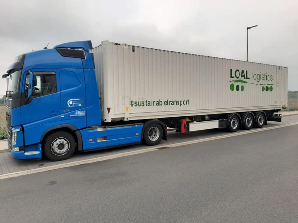 Ansamblu cap tractor si semiremorca cu container maritim fotografiat in parcare