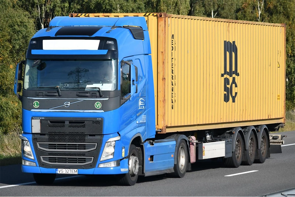Ansamblu cap tractor Volvo si semiremorca pentru transport de containere fotografiat in mers pe autostrada